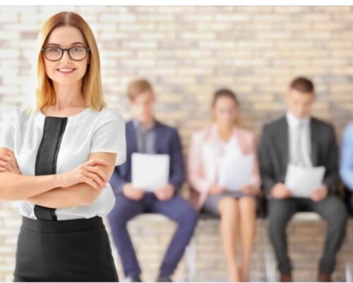 How to succeed in an office job: A woman standing in a professional background. It's good to know your employer's expectations of yourself.